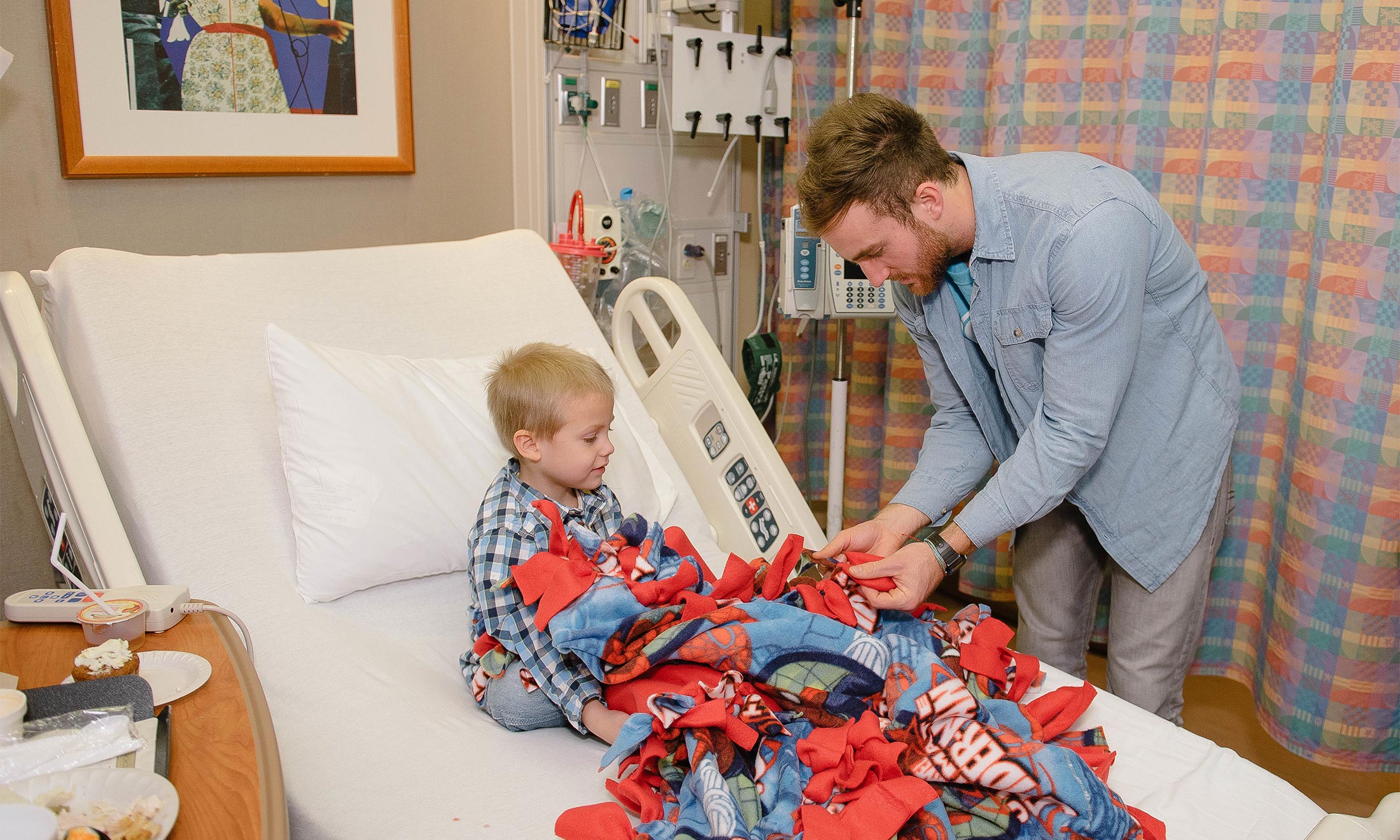 Nick Kristock gives a blanket to a sick child in the hospital