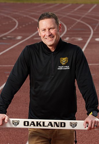 A man standing on the track with a hurdle
