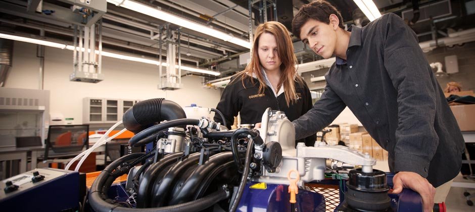 Male and Female students working on the engine of a race car