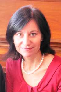 woman in a red shirt and pearl necklace smiling at the camera