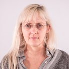 woman wearing a gray shirt and glasses, looking at the camera