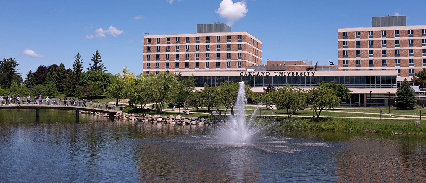 A building exterior with the words Oakland University, behind Bear Lake.