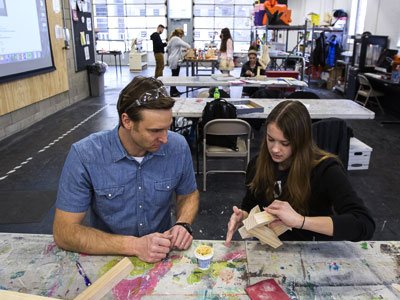 Man and woman sitting at a table working on an art piece