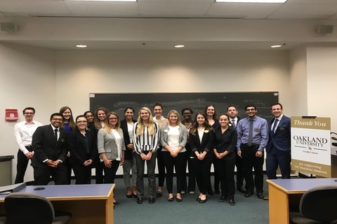 group photo of business scholar students in a classroom with a sign that says "Thank You Oakland University"