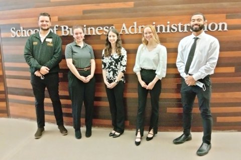Leo Kaçaj, Mari Romund, Alexis Harp, Lauren Goralczyk and Kurtis Jackson standing in front of a wall with School of Business Administration on it.