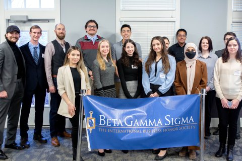 A group of honor society students standing behind a banner that reads "Beta Gamma Sigma".