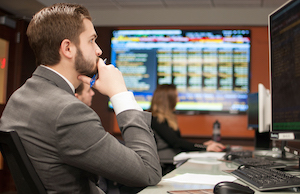 A male student seated at a desk on the trading floor in Elliott Hall.