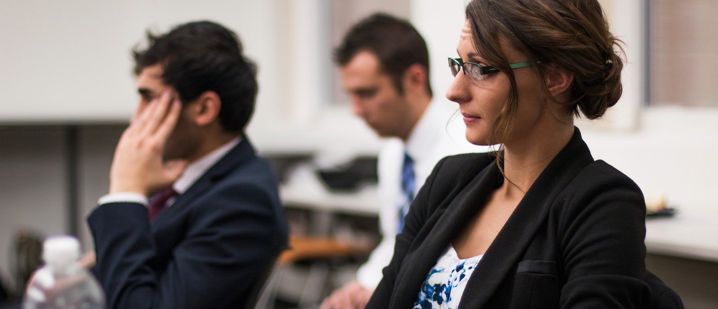 Actuarial Science Three adults in business attire, seated at desks.