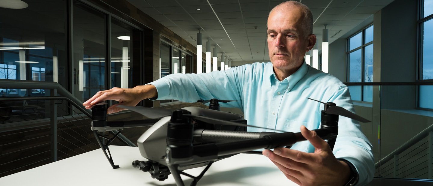 Business Research A man seated at a table, holding a drone.