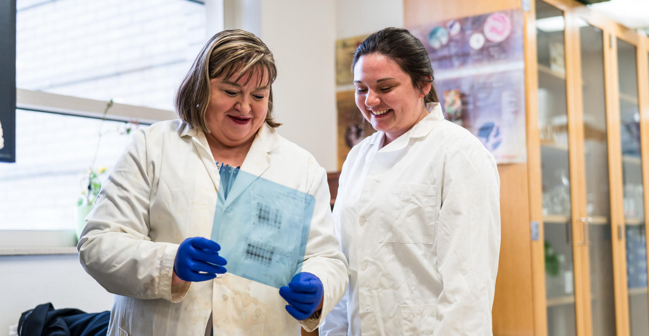 OU faculty and student in white lab coats looking at lab results