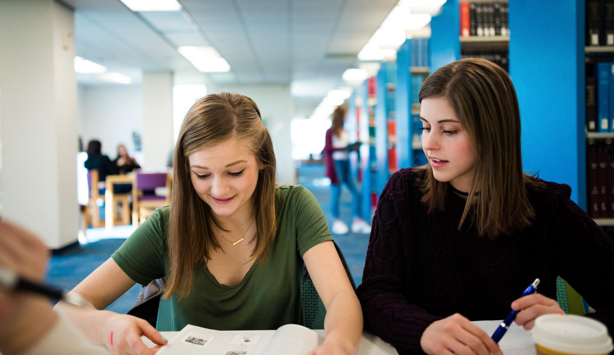 Two students sitting at a library table working together