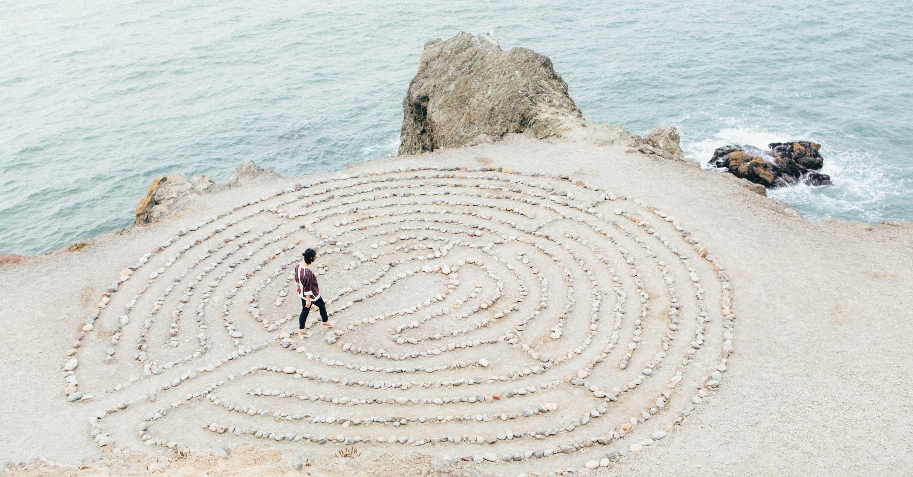 Woman walking through a meditation maze on a beach