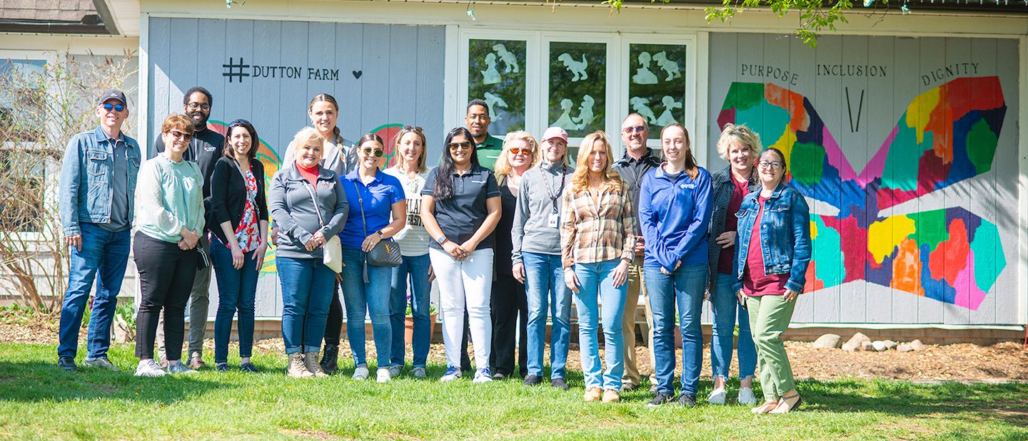 Employer Sponsorship A group of people posing in front of a Dutton Farms building.