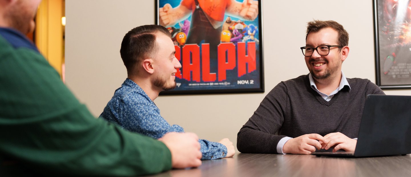 For Employers Three men seated around a table talking.