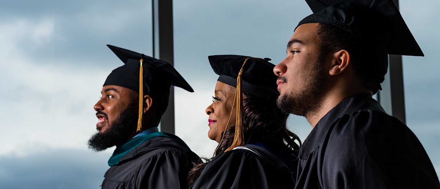 Three African American students in their graduation caps and gowns.