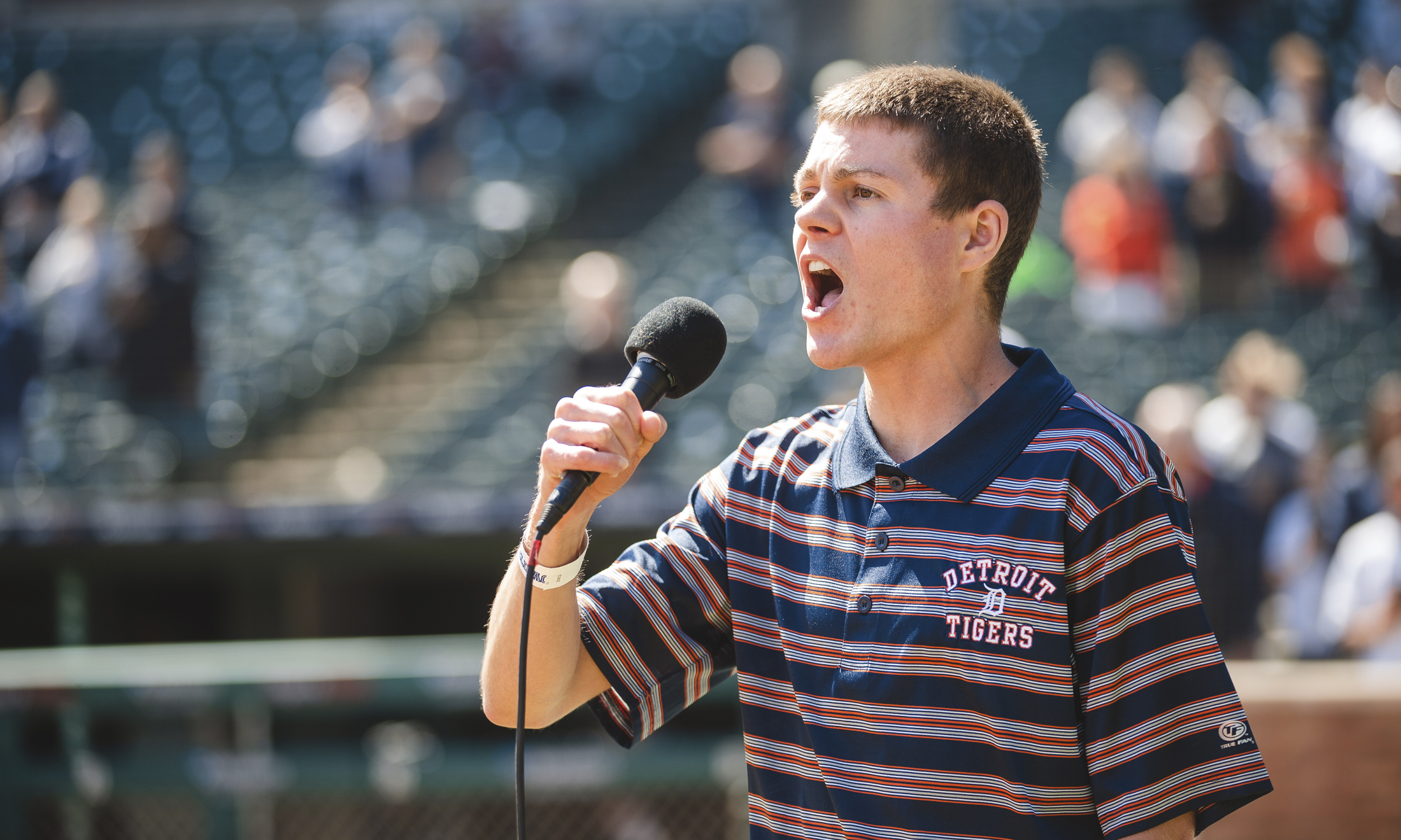 Photo of a young man singing into a microphone at comerica park