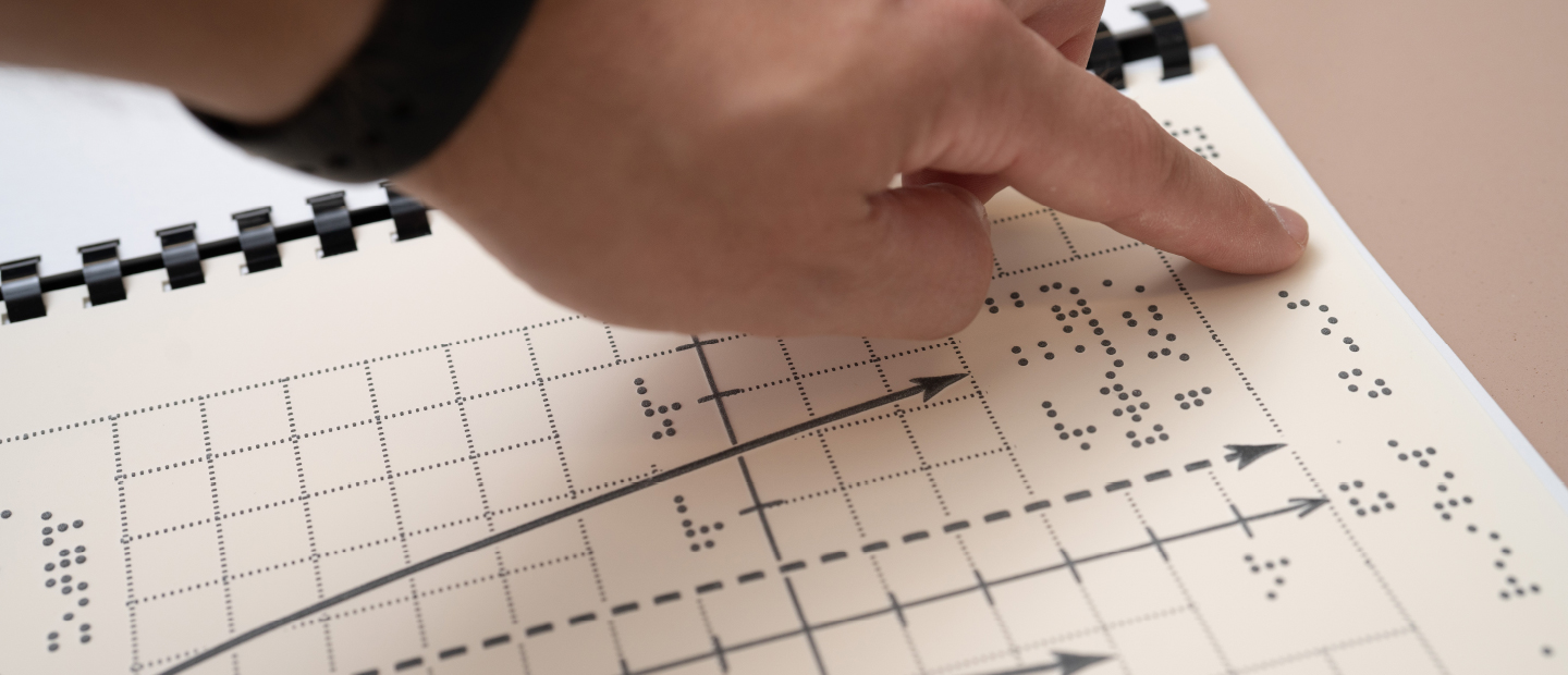 finger reading Braille in a notebook