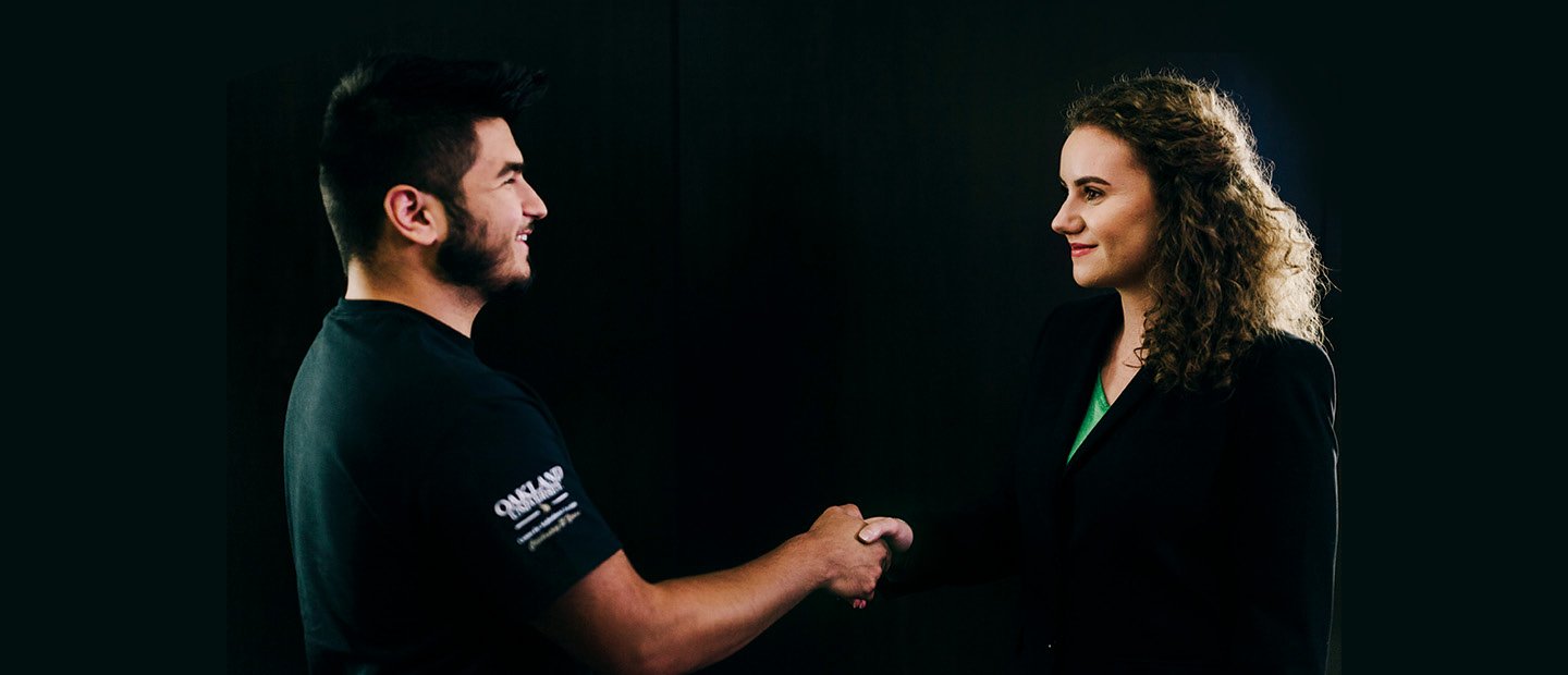 man and woman in black shaking hands against a black background