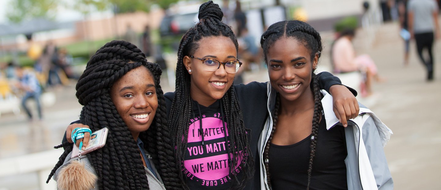 three women with their arms around each other, posing for a photo