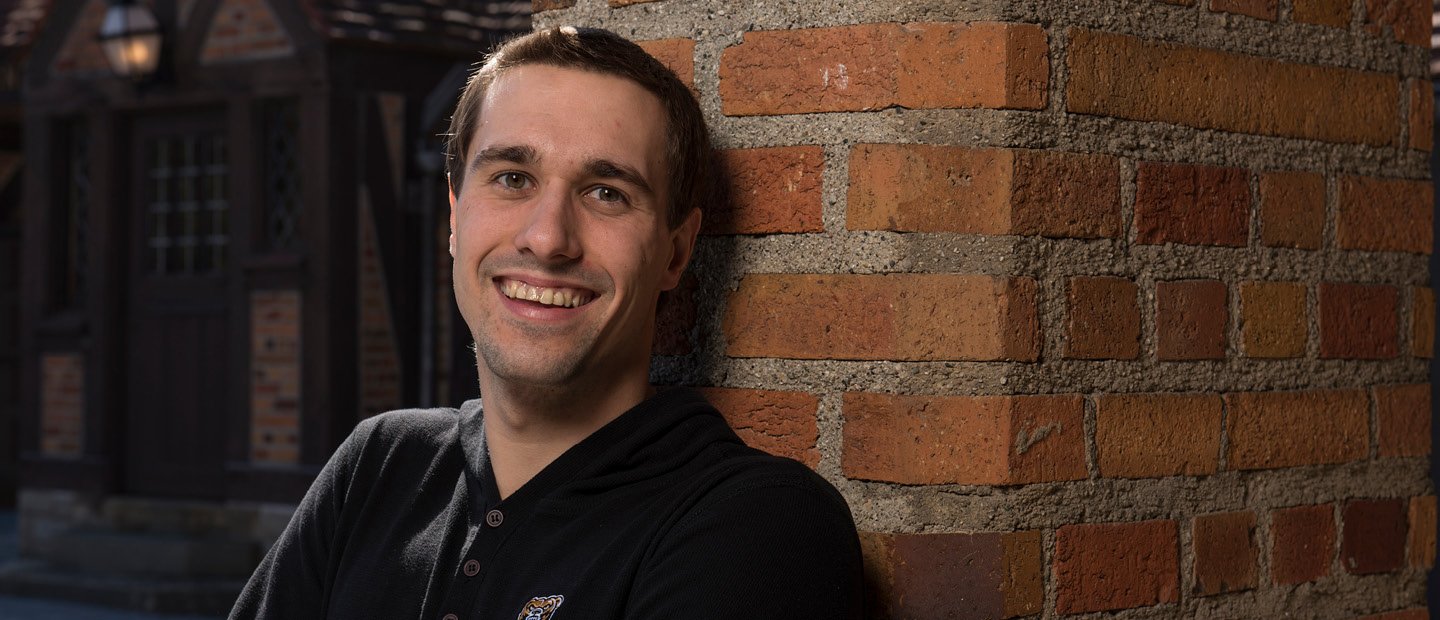 man in a black shirt leaning on a brick wall