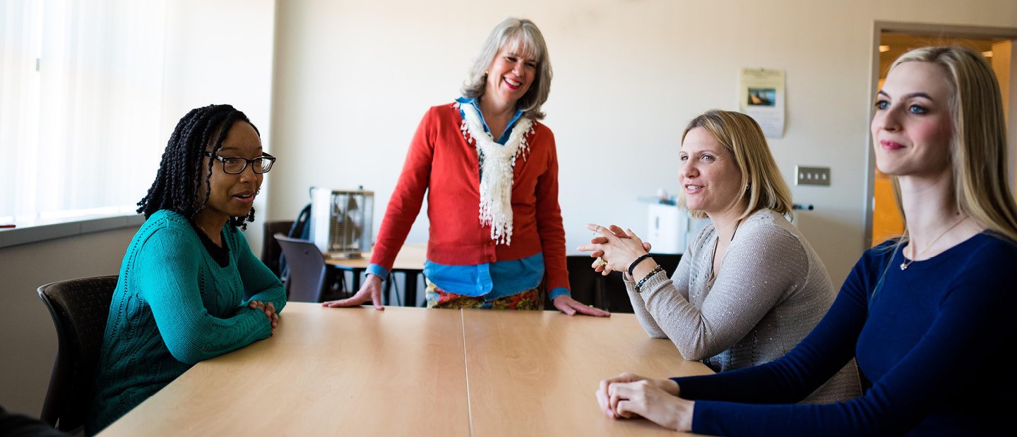 four women around a table in an office