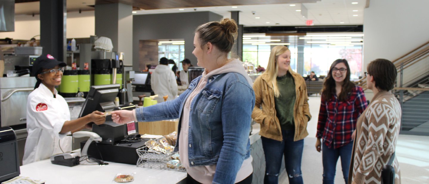 woman handing a card over a counter to a cashier in a dining center 