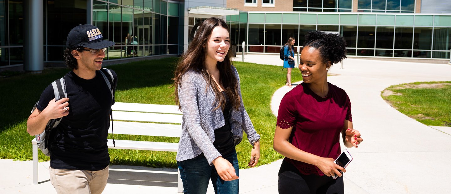 Housing Options three students walking outside on campus with buildings in the background