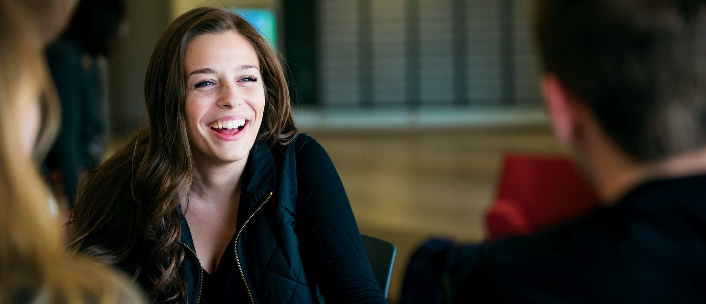 Policies Procedures Smiling female student in a black shirt seated across from other people