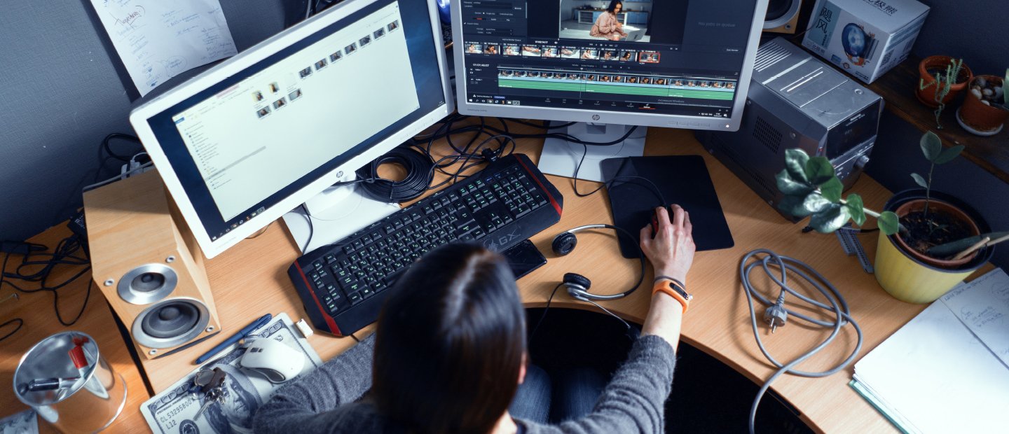 A student editing film at a computer desk.