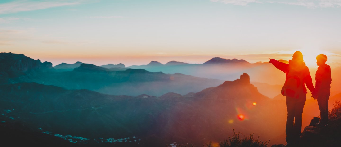 Two people standing on a peak overlooking mountains.