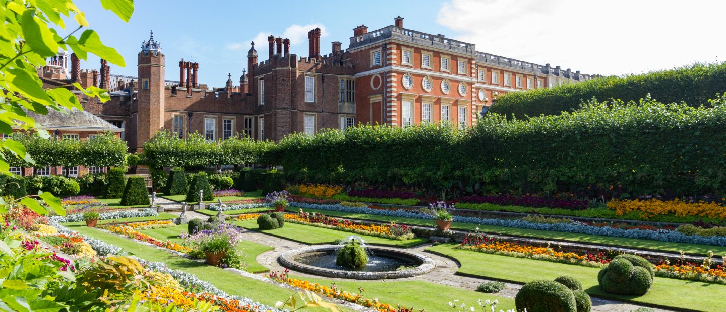 A large Tudor manor house with a garden area in England.
