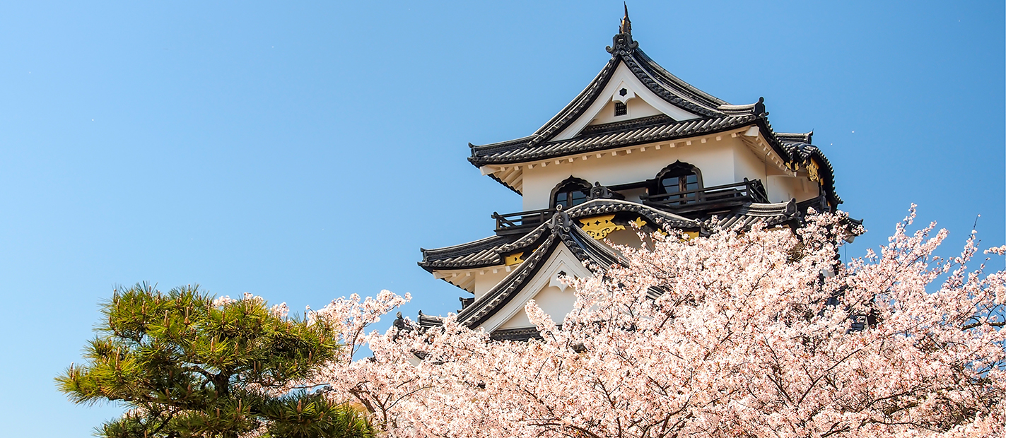 The top of a building in Japan with trees in front of it.