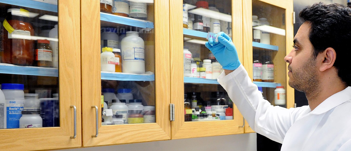 A man standing in front of a cabinet full of biological and medical supplies.