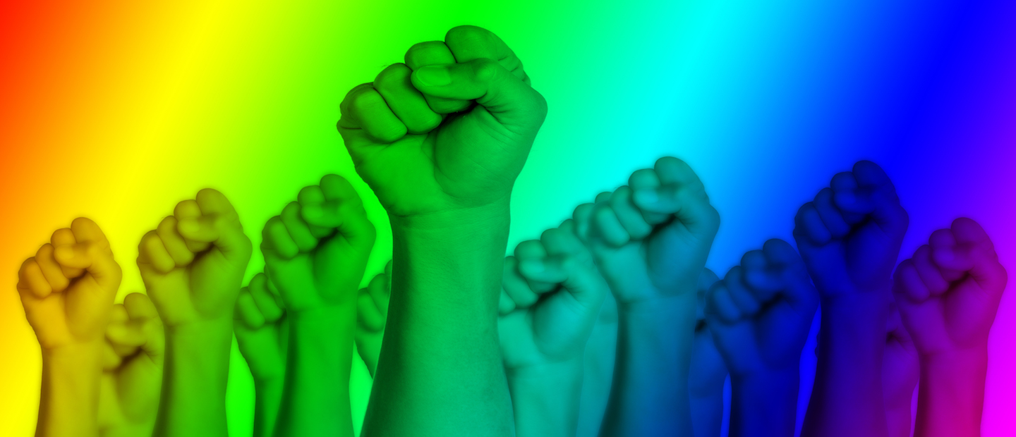 Fists raised in the air with a rainbow colored overlay on the image.