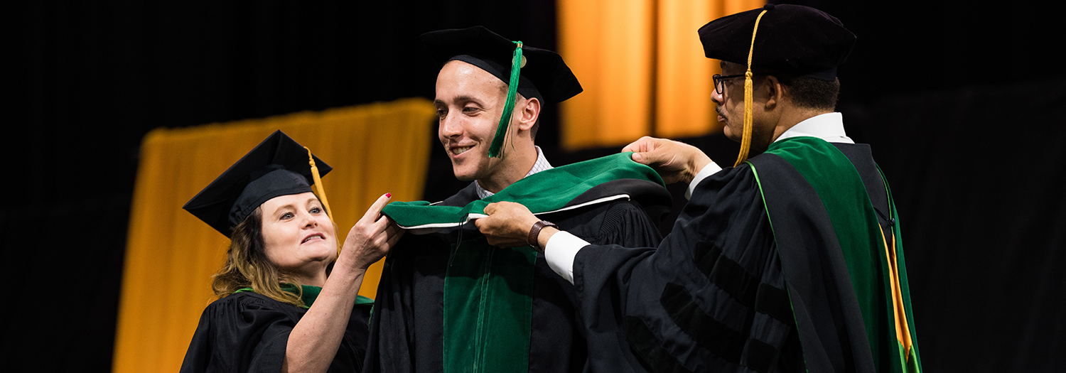 An image of a graduate being hooded at commencement