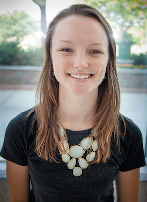 woman in a black shirt standing outside, smiling at the camera