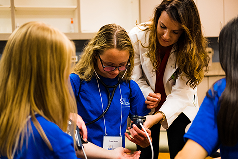 Monica Szmyd in a white lab coat teaching students at a summer camp