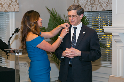 Woman placing a pin on the lapel of Dr. Robert Folberg, M.D.