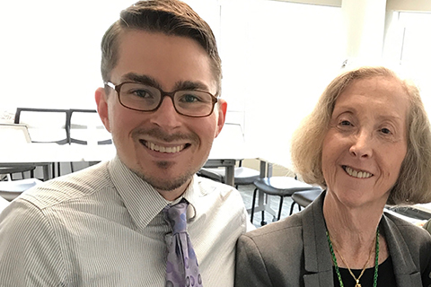 Triska and Professor young man in a shirt and tie posing for a photo with an older female professor in a classroom