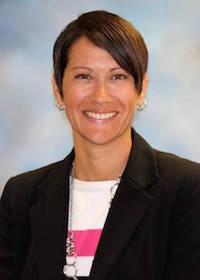 woman in a black suit jacket smiling at the camera