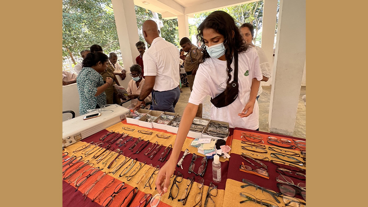 An image of a student prepping glasses for distribution