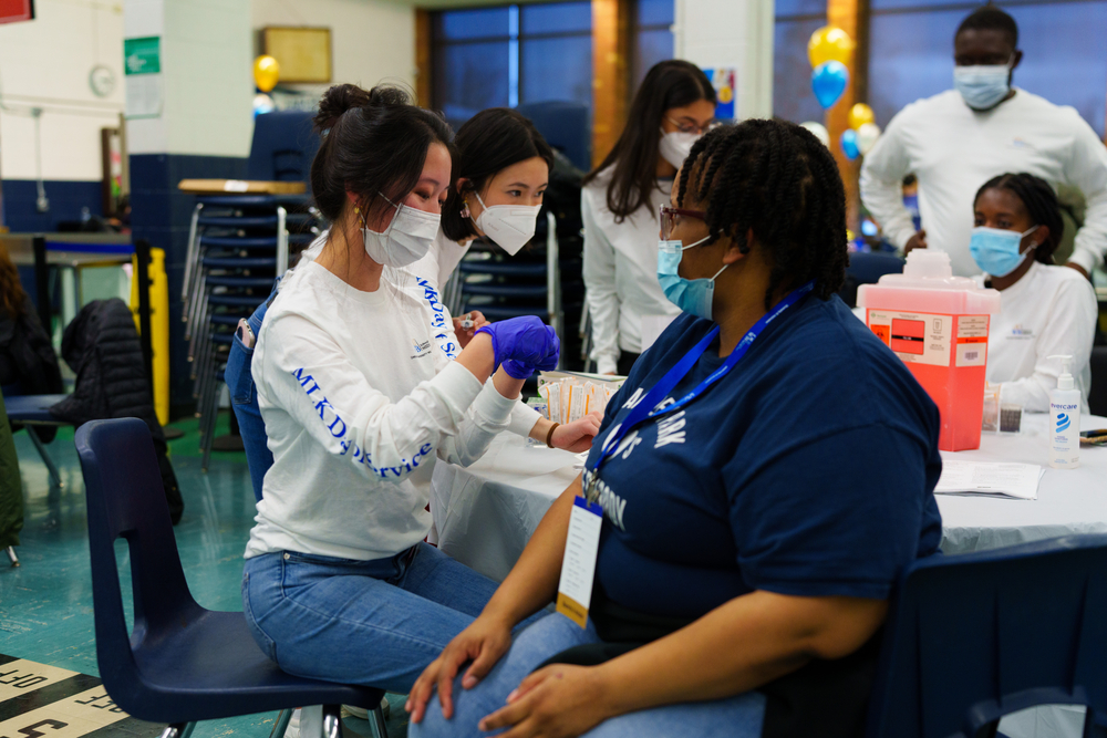 An image of a student from OUWB giving a flu shot
