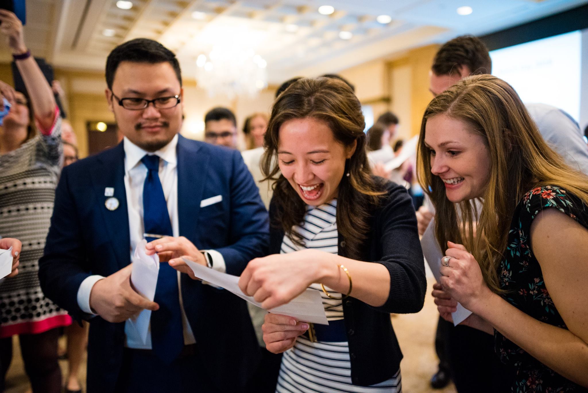 Student happily reads her match day letter with friends looking on.