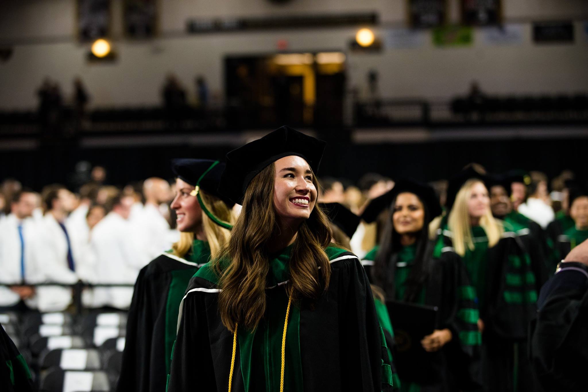 Smiling student wearing cap and gown at graduation ceremony.