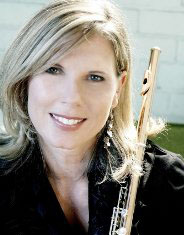 woman in a black jacket, holding a flute, smiling at the camera