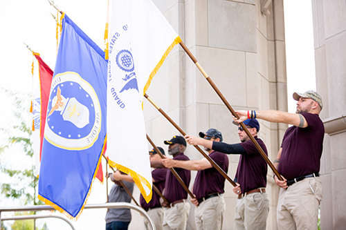 Student veterans standing in front of Elliott Tower and holding military branch flags