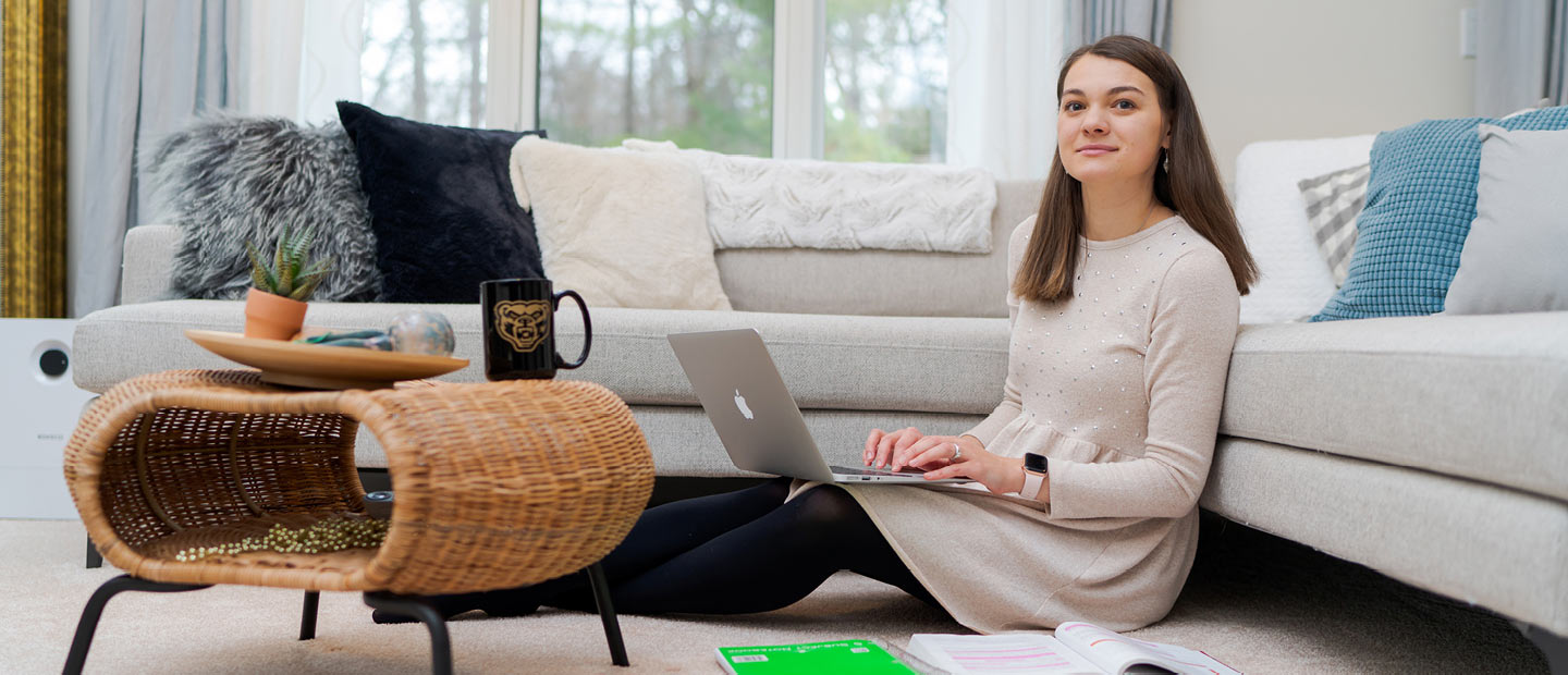 Woman sitting on living room floor working on a laptop