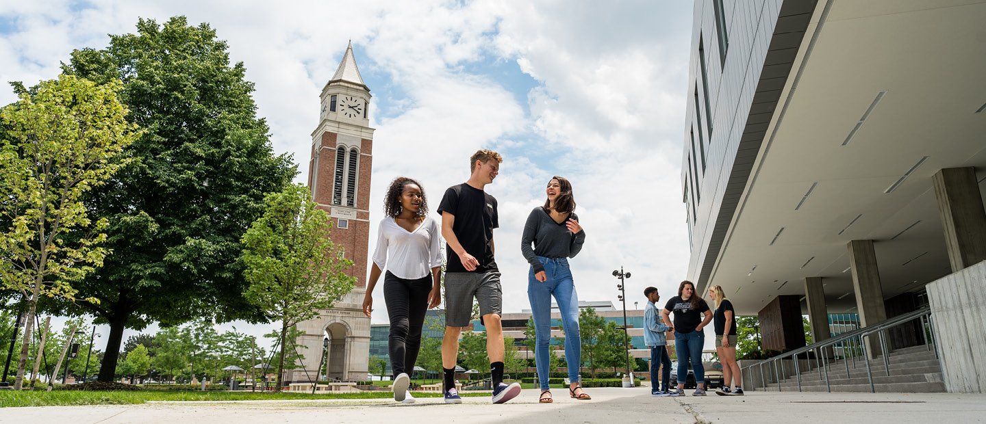 Compliance and Disclosures students walking on Oakland University's campus with a clock tower in the background