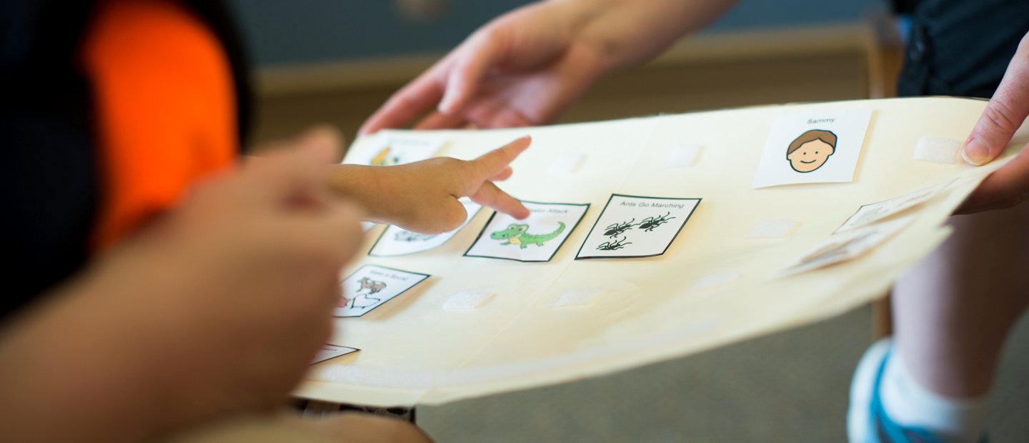A child's hand pointing to cards with animals on them.