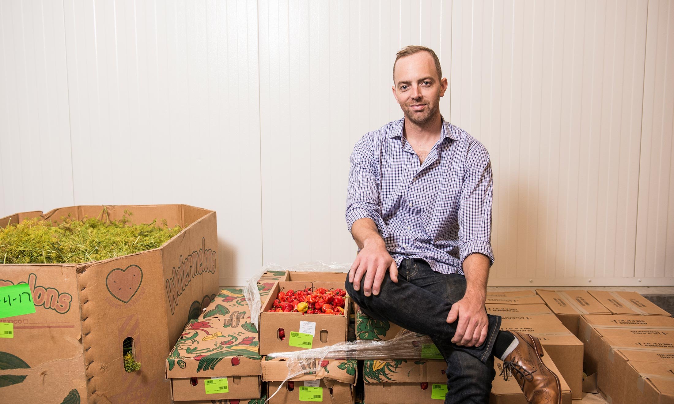 Joe McClure sits in the McClure Pickles warehouse next to fresh dill and peppers